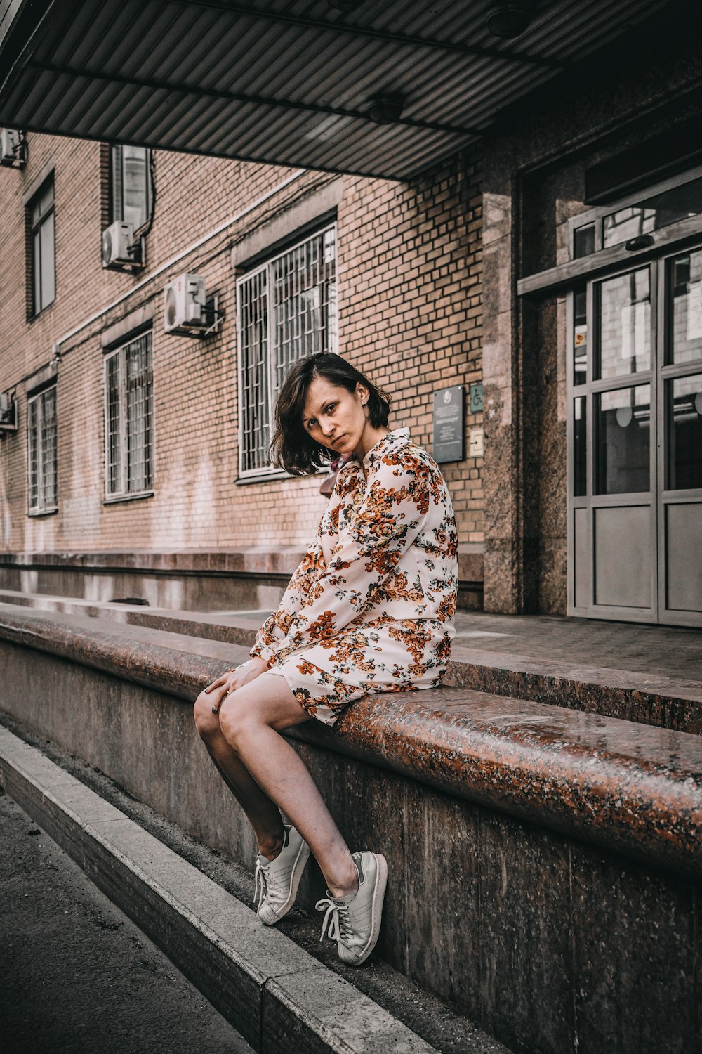 a woman sitting on a ledge in front of a building