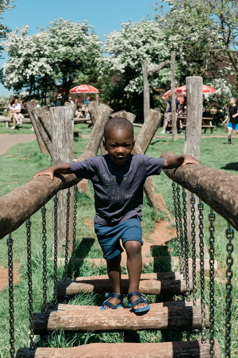 a little boy standing on a wooden bridge