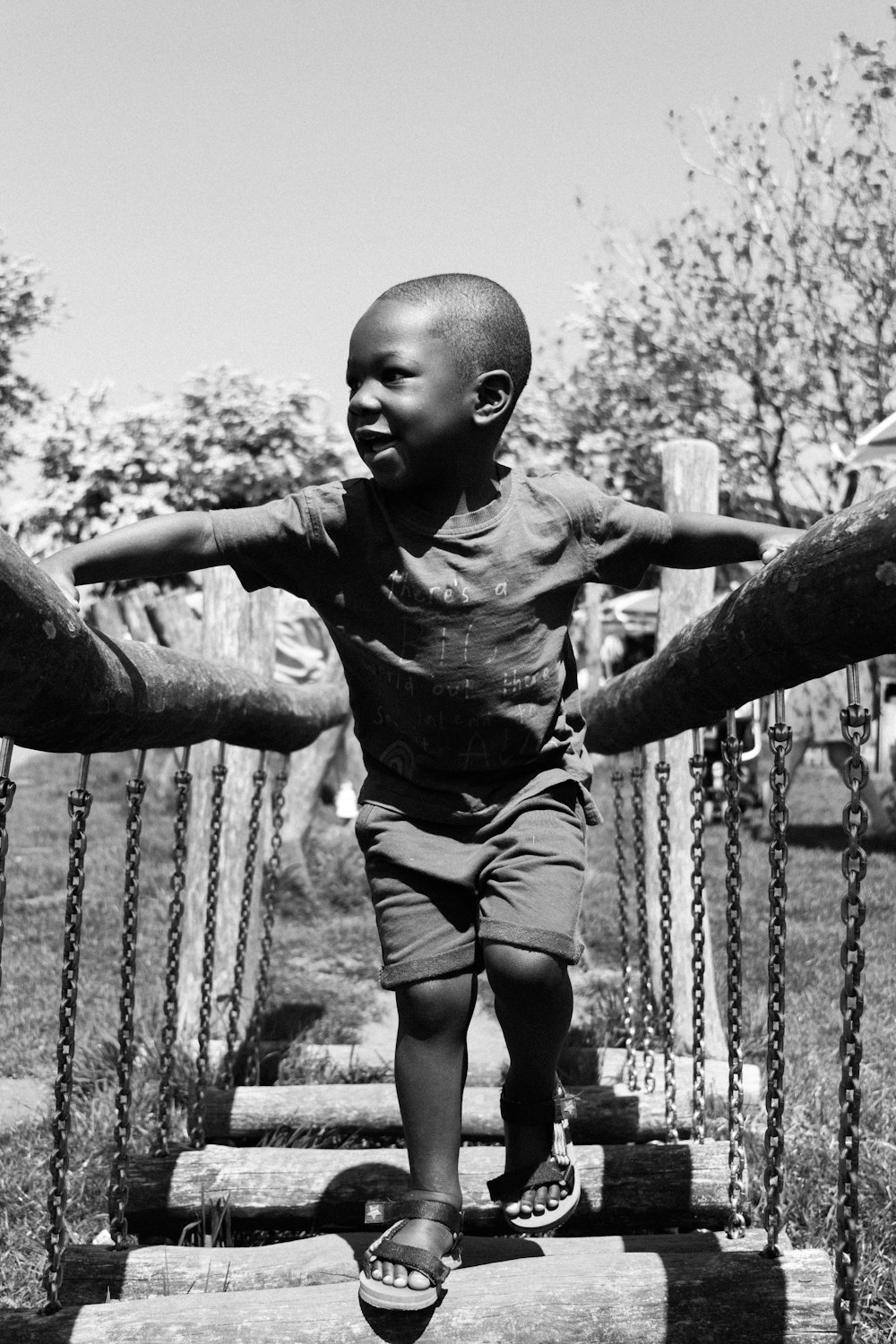 a young boy walking across a wooden bridge