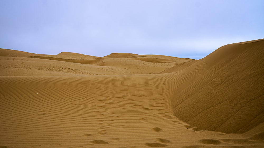 a person walking across a large sandy field