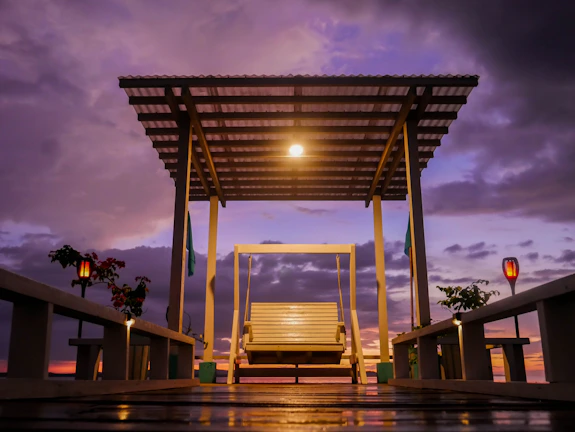 Dusk view of a timber deck with warm integrated lighting and elegant pergola framing a cozy outdoor dining area.