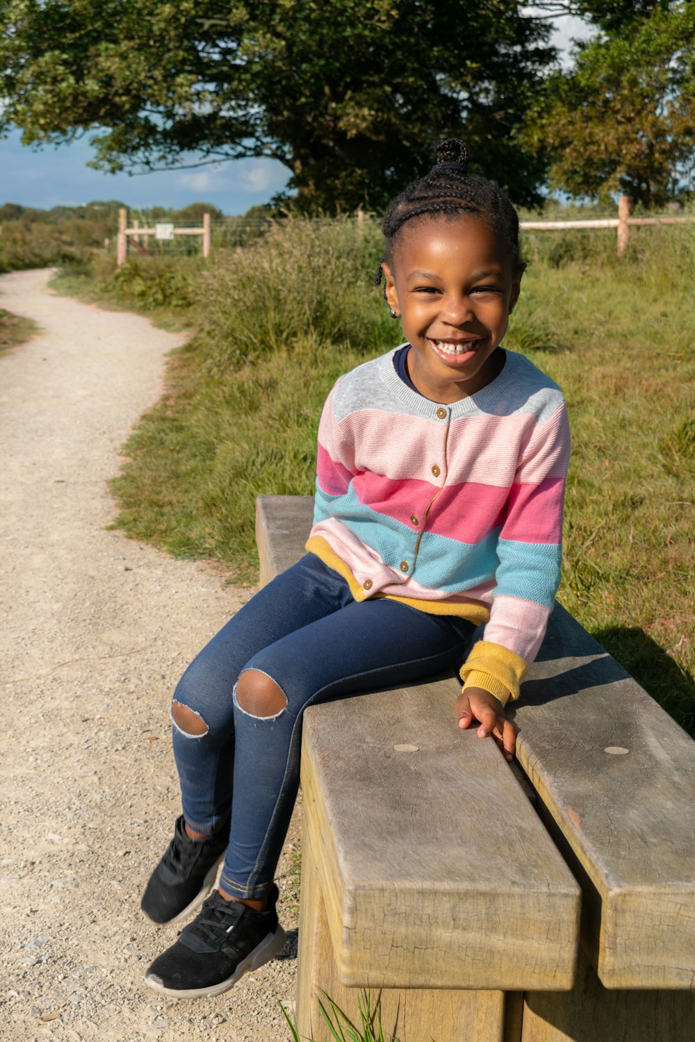 a young girl sitting on a wooden bench