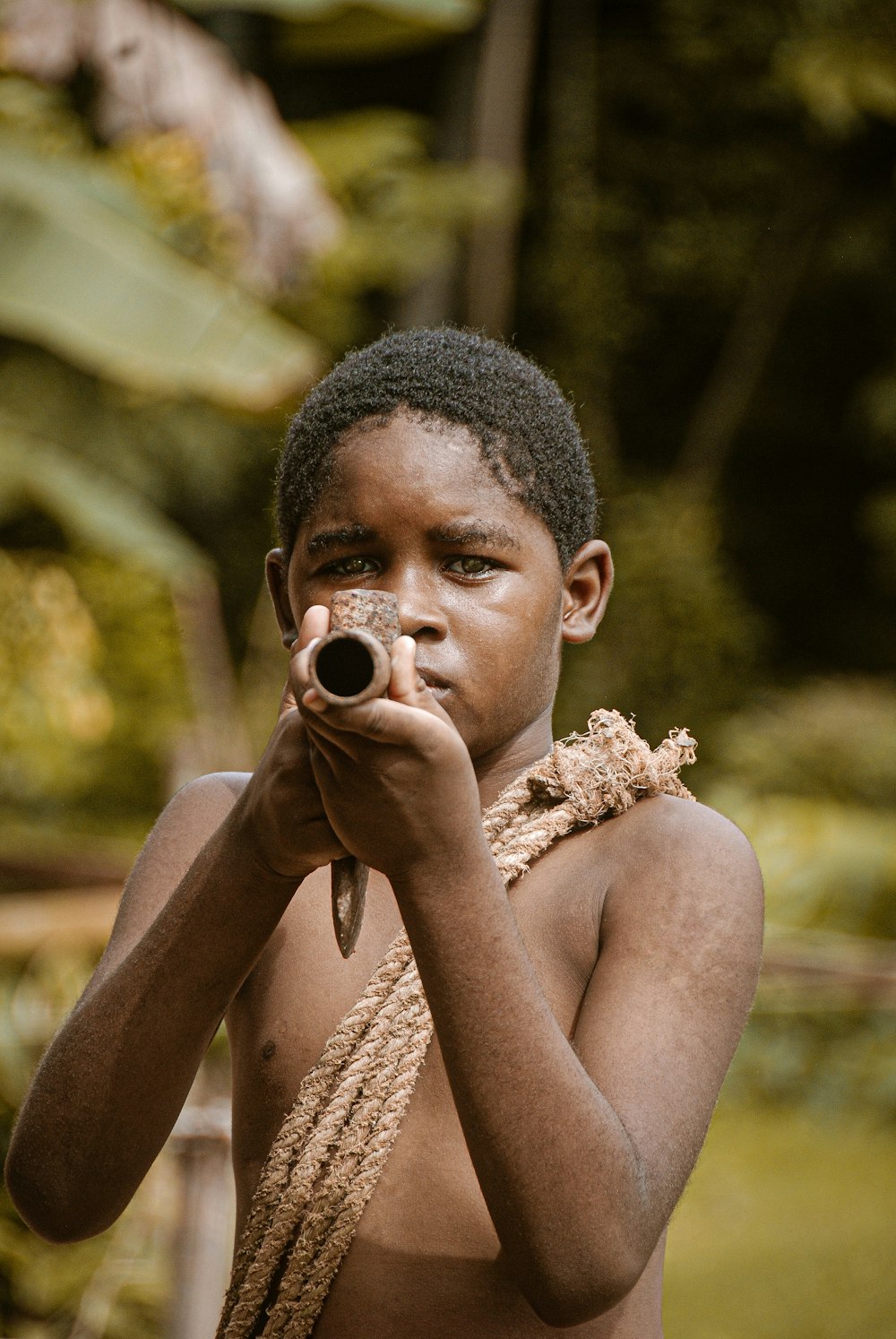 a young boy holding a gun in front of his face