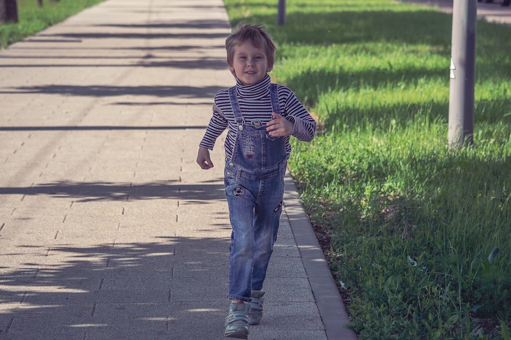 a little boy that is walking down a sidewalk