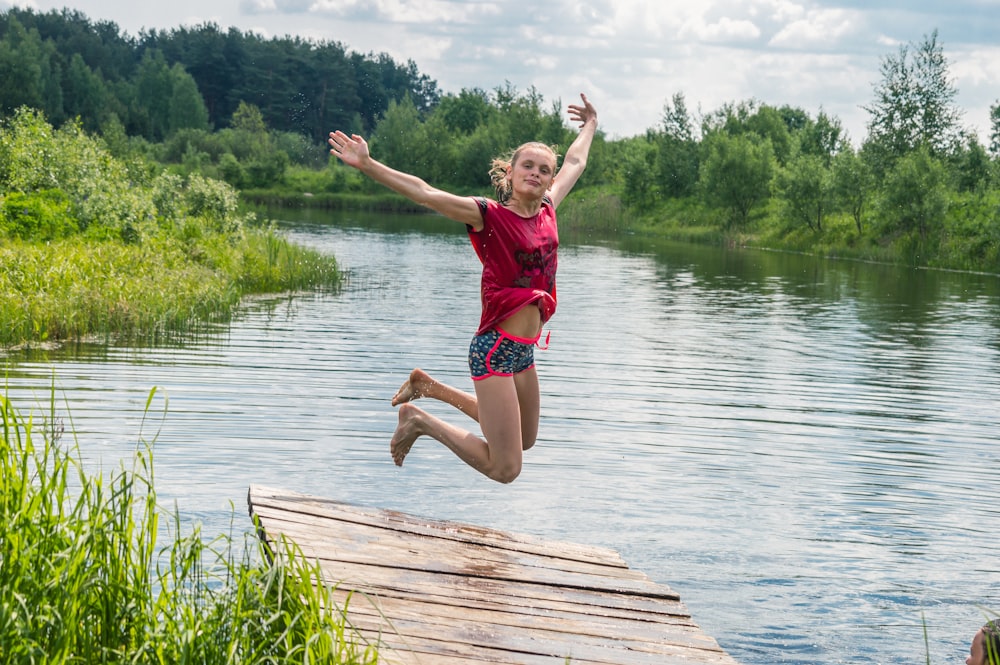 a girl jumping off a dock into the water