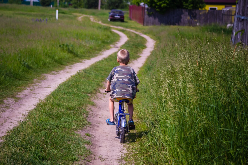 a young boy riding a bike down a dirt road