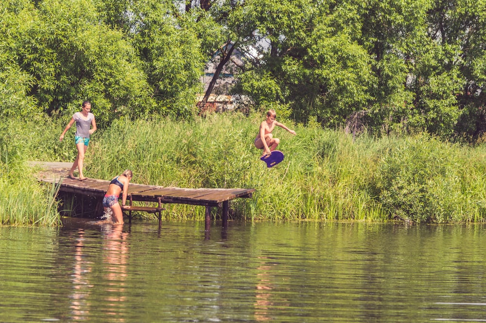 a group of people jumping off a dock into the water