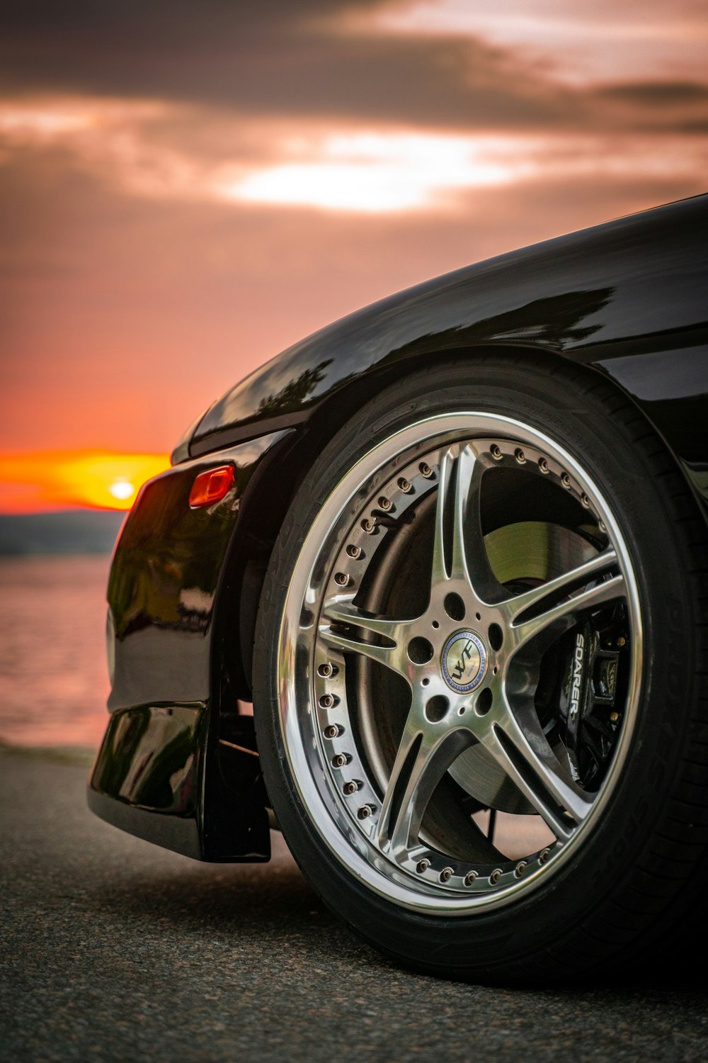 a close up of a car with a sunset in the background