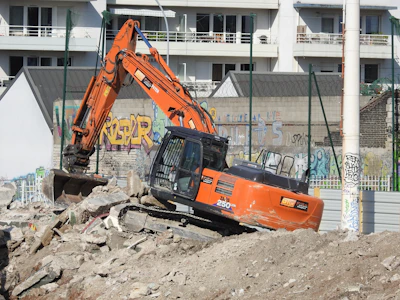 an orange excavator digging through a pile of rubble