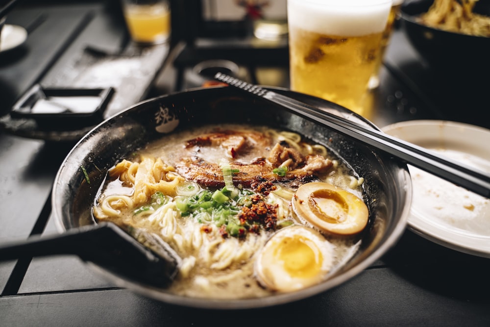 una ciotola di ramen con bacchette e un bicchiere di birra