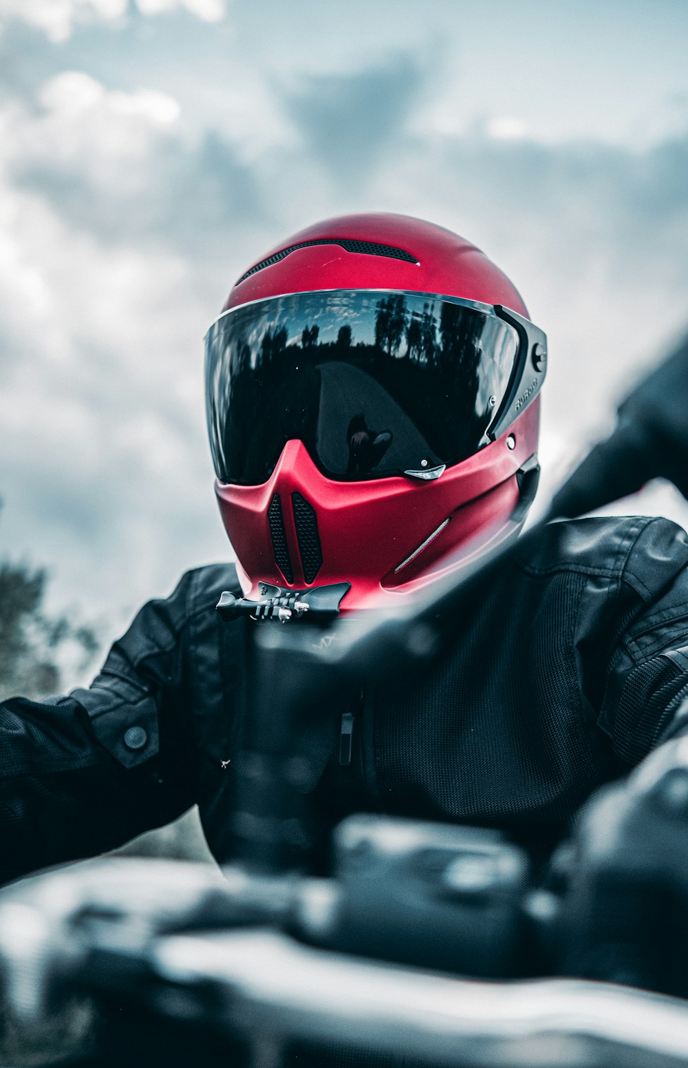 a person wearing a red helmet and black jacket sitting on a motorcycle