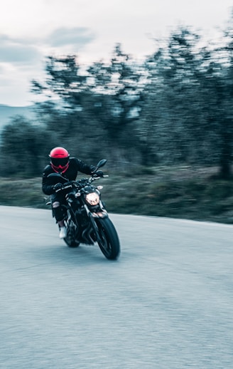 A dynamic photo of a red motorcycle speeding on an open road under a clear sky