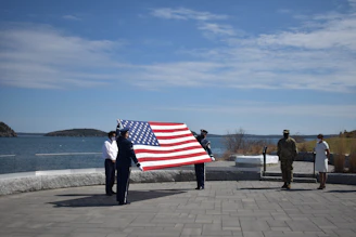A group of local volunteers proudly displaying a large American flag at a community event.