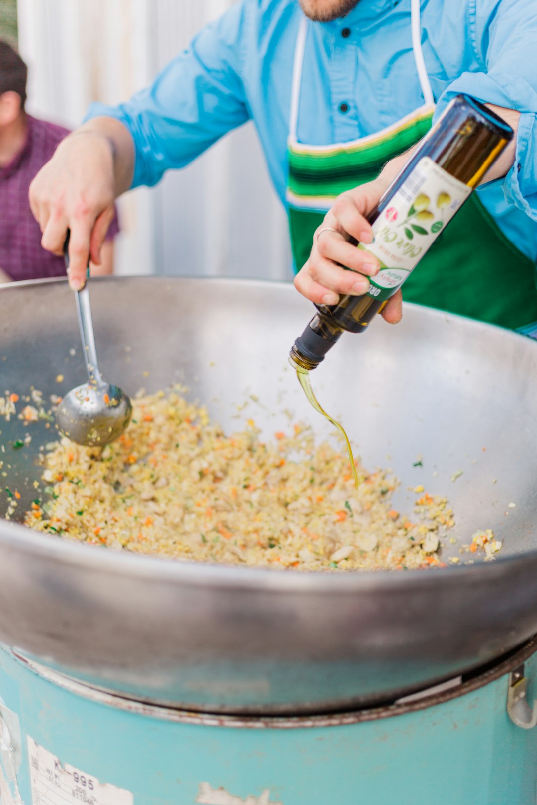 person holding green glass bottle pouring white rice on stainless steel bowl