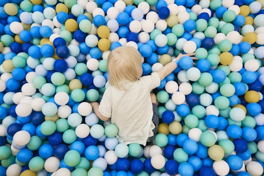 a little boy standing in a ball pit