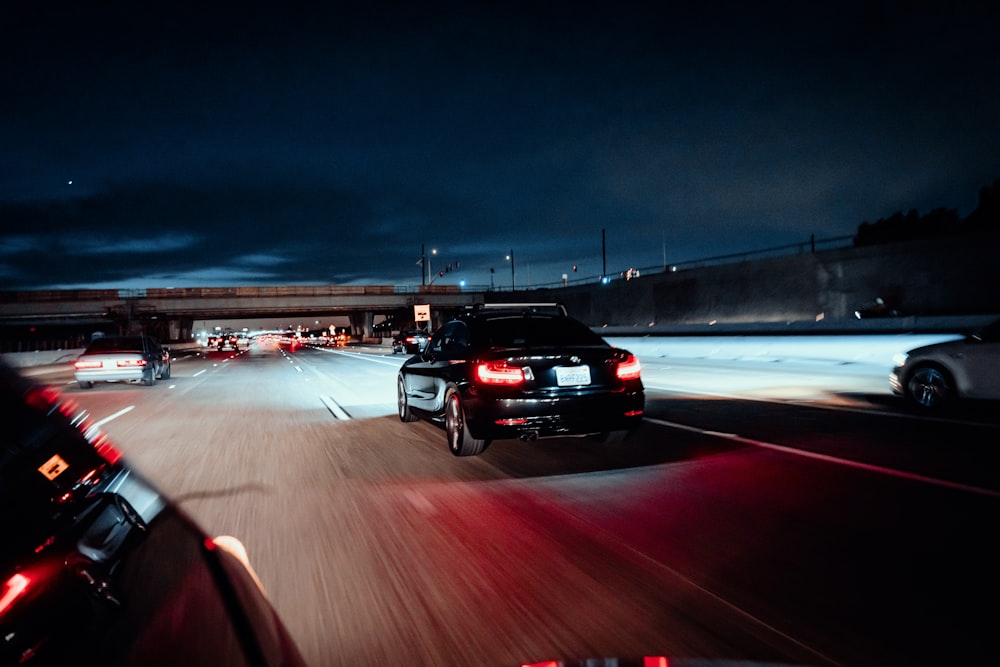 a couple of cars driving down a street at night