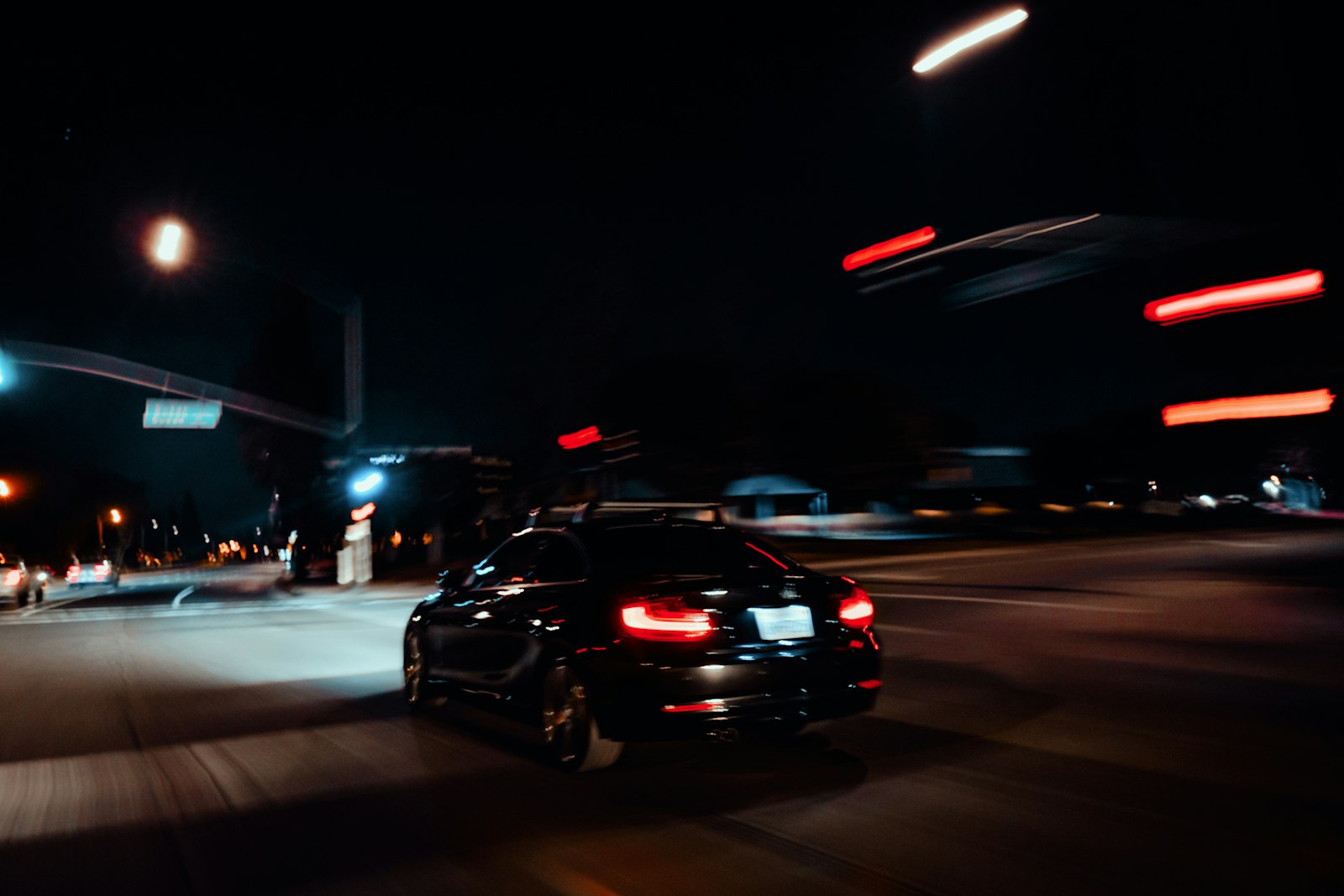 A car driving down a dark street at night with its headlights lit