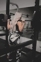 a woman in a black and white outfit lifting a barbell