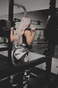 a woman in a black and white outfit lifting a barbell