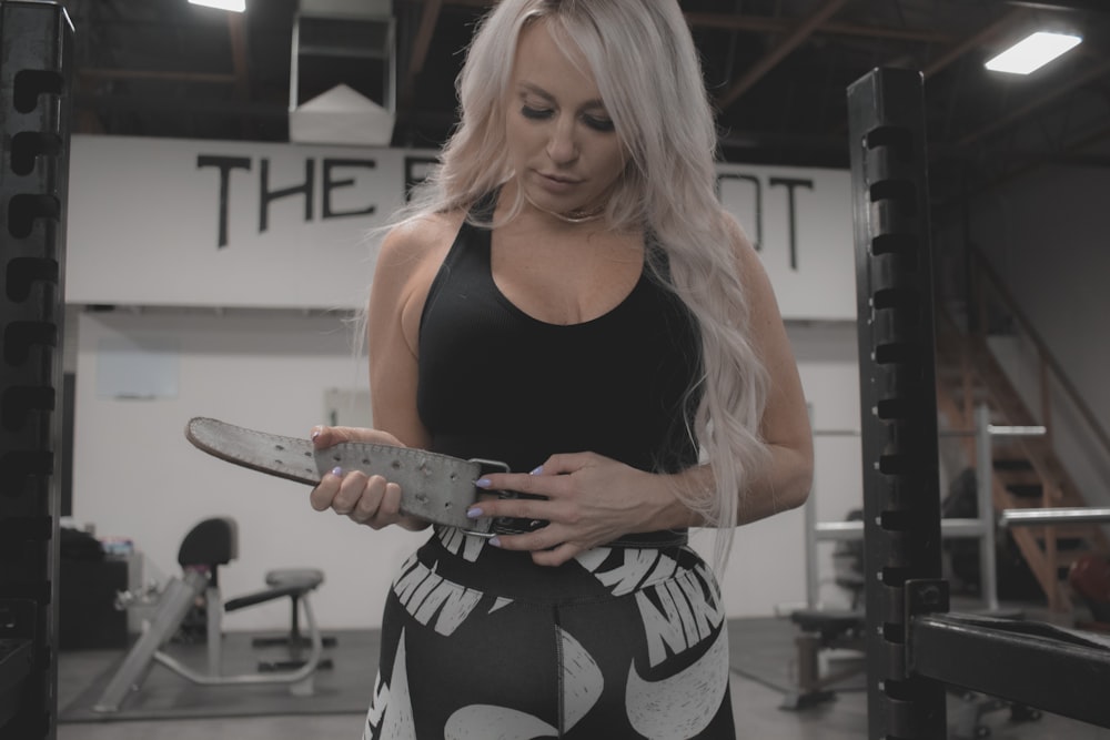 a woman holding a skateboard in a gym