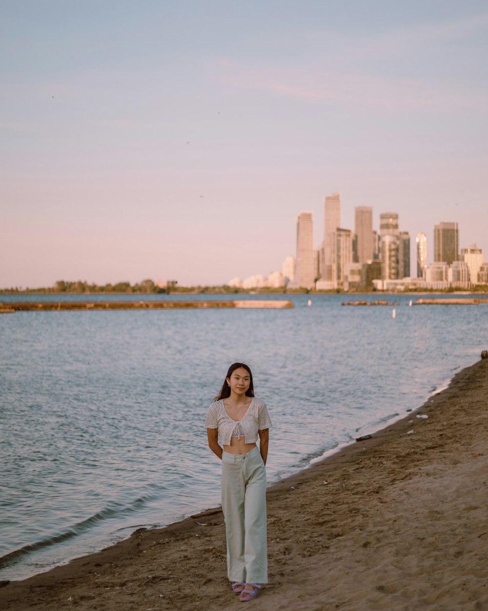 a woman standing on a beach next to a body of water