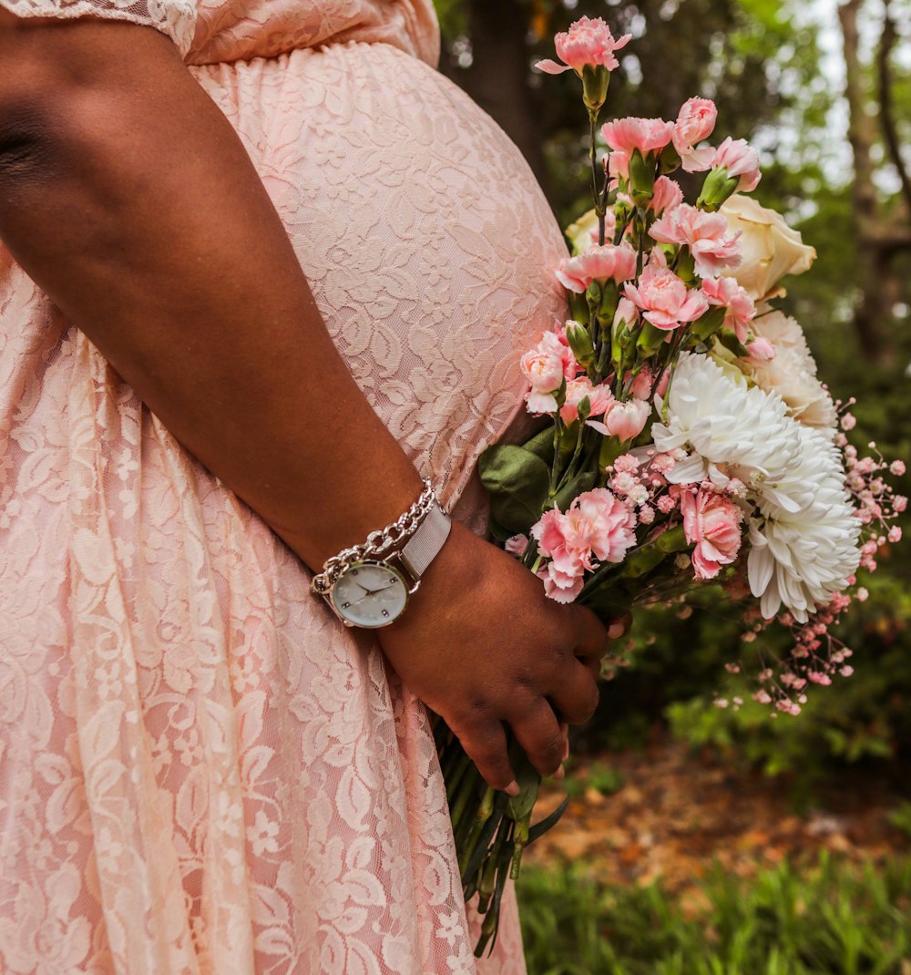 a pregnant woman holding a bouquet of flowers