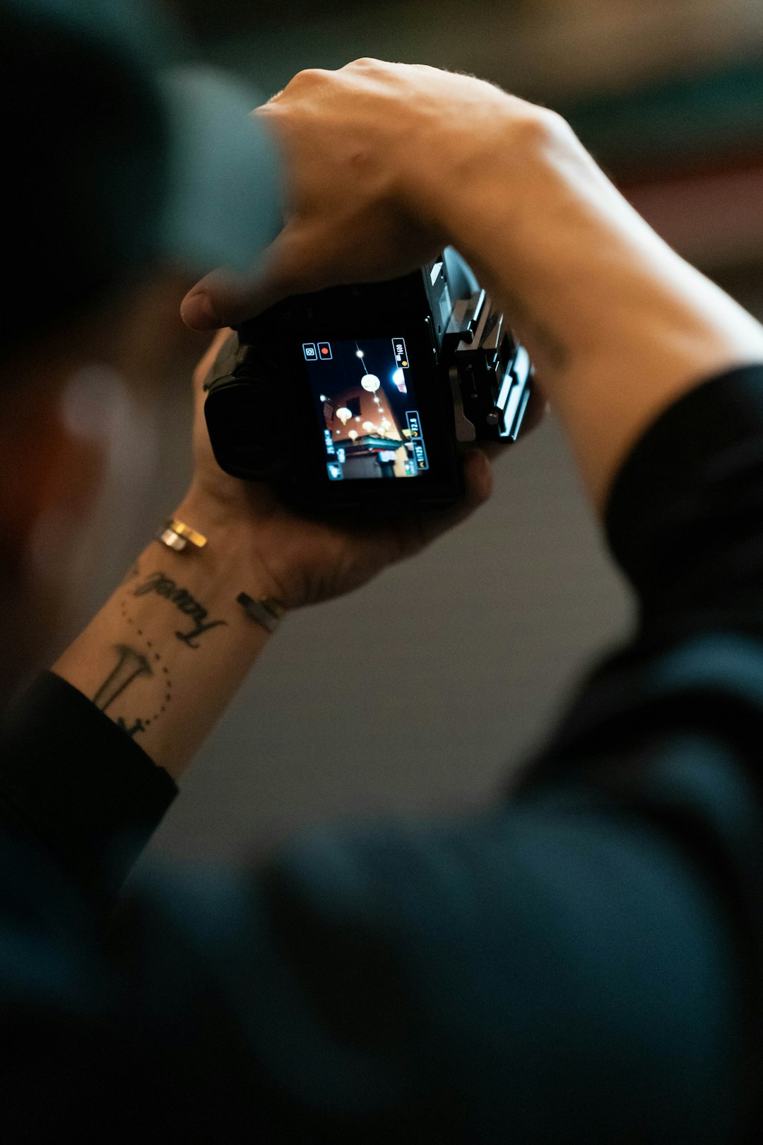 person holding black smartphone taking photo of man with tattoo on his left hand