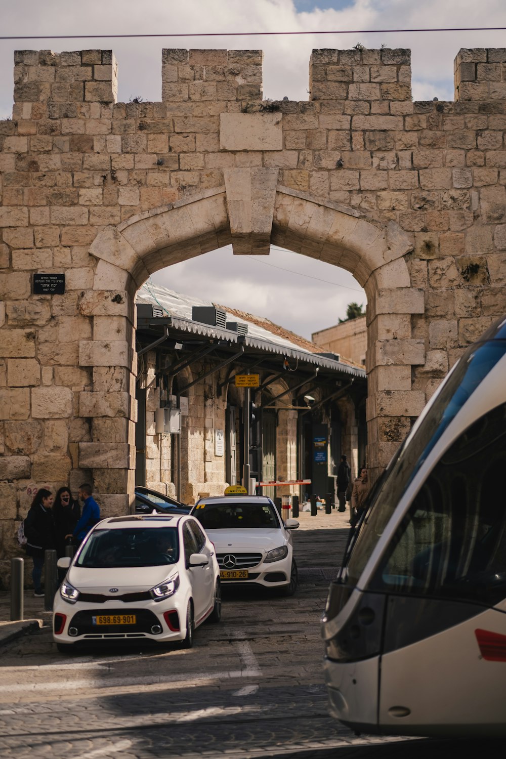 a white car driving down a street next to a stone wall
