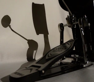 Modern kick pedal with noise-reducing features on a dark background.