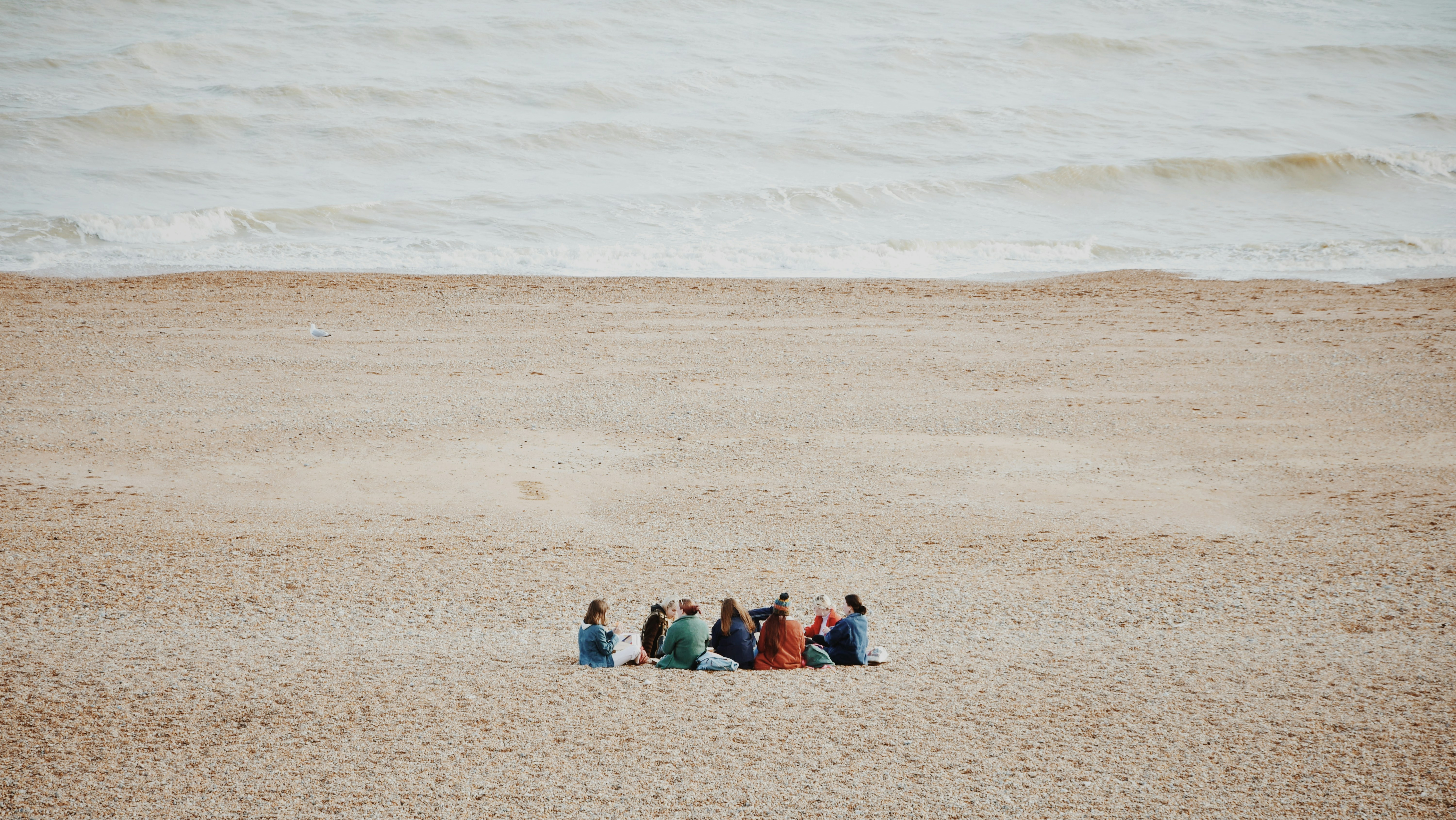 a group of people sitting on top of a sandy beach