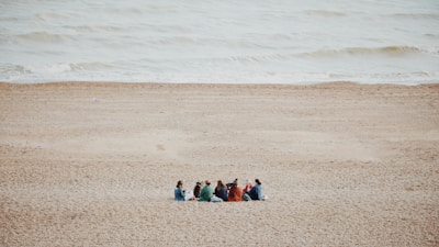 a group of people sitting on top of a sandy beach
