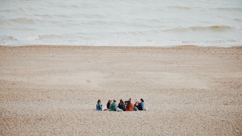 a group of people sitting on top of a sandy beach