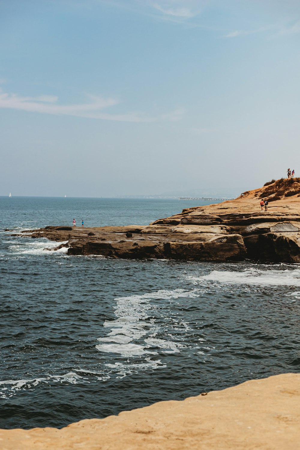 brown rock formation on sea under blue sky during daytime