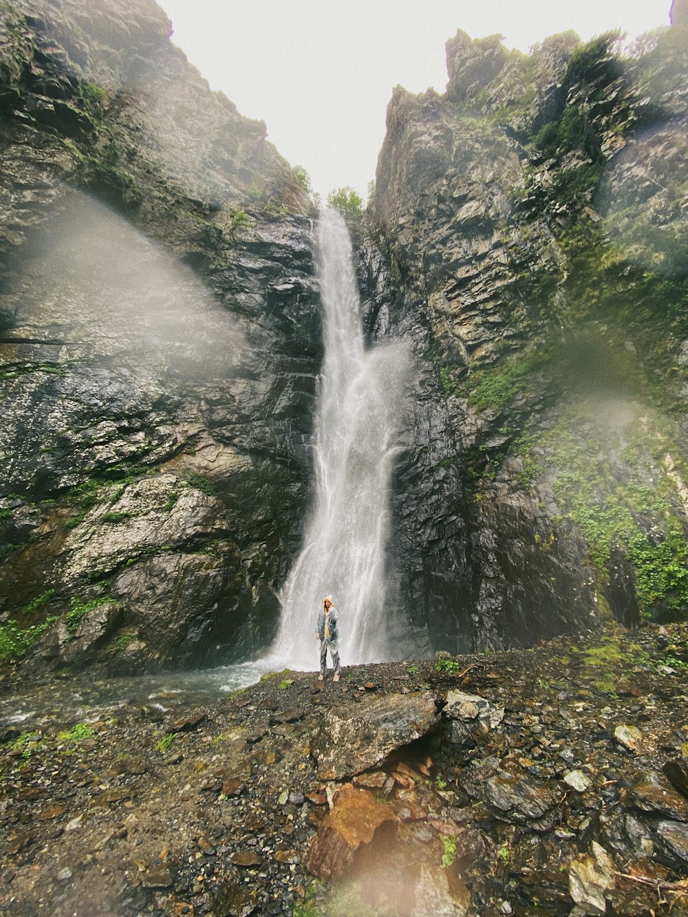 person standing on rock near waterfalls during daytime