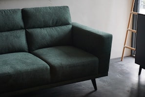 teal cushion armchair in front of a white wall