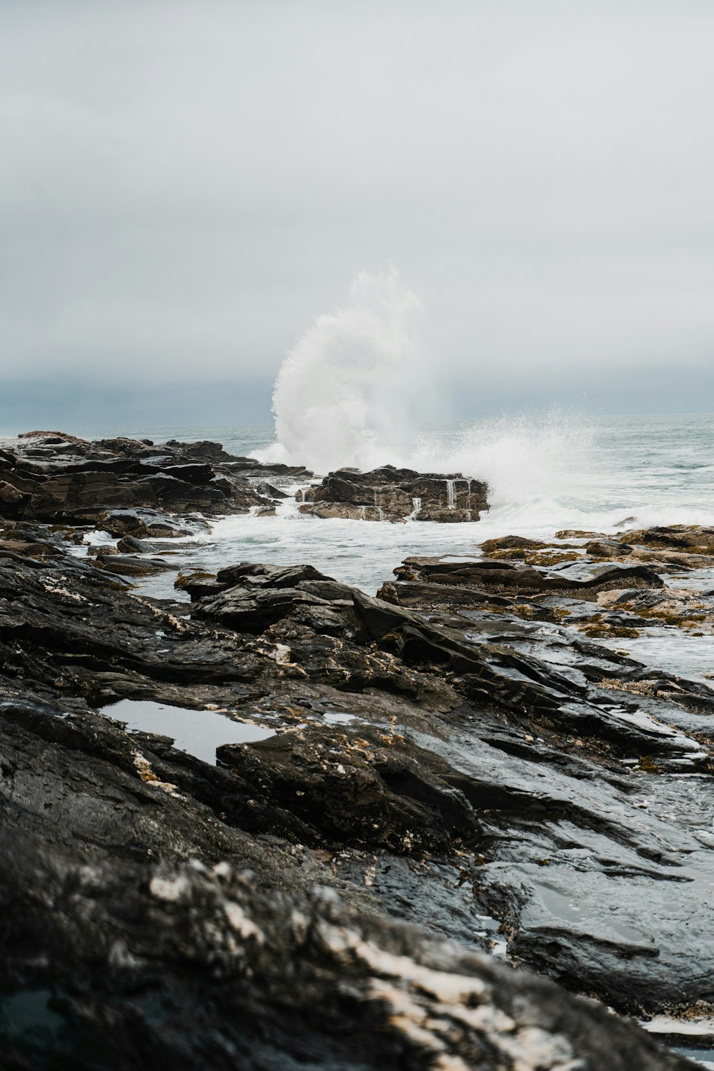 a large wave hitting the rocks on the beach