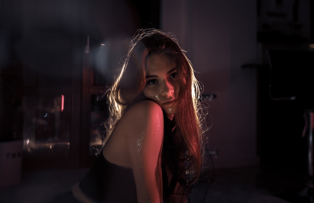 a woman with long hair standing in a dark room