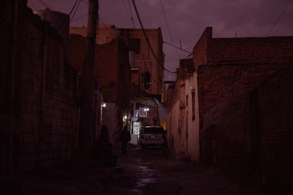 a dark alley way with a car parked on the side