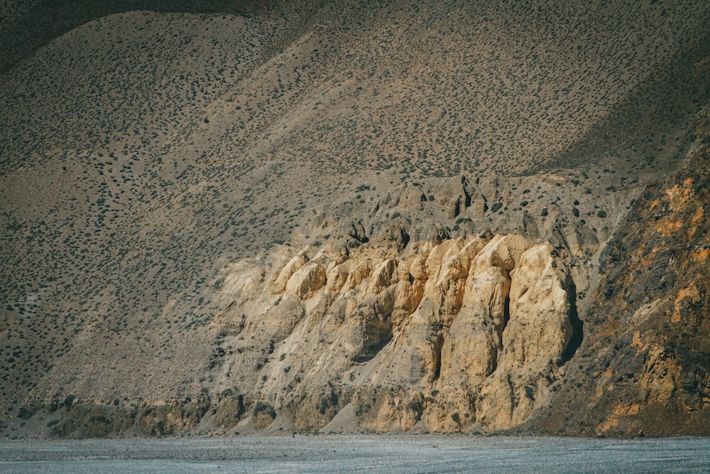 a mountain side with a body of water in front of it