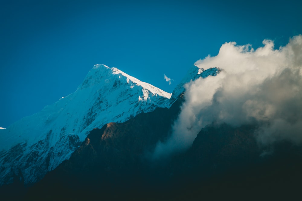 a snow covered mountain with clouds in the foreground