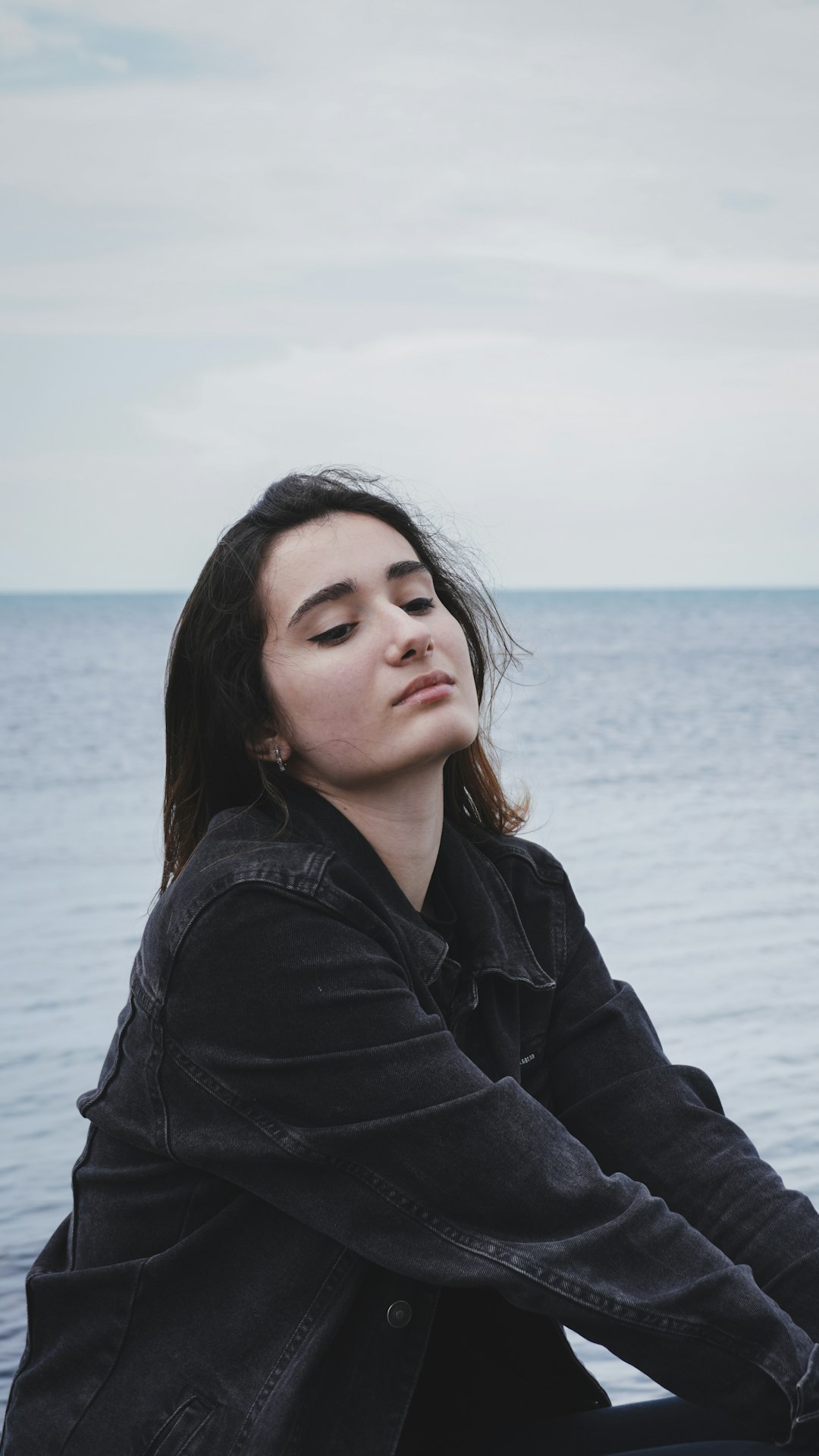 woman in black jacket standing near sea during daytime