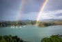 two rainbows over a lake with boats in the water