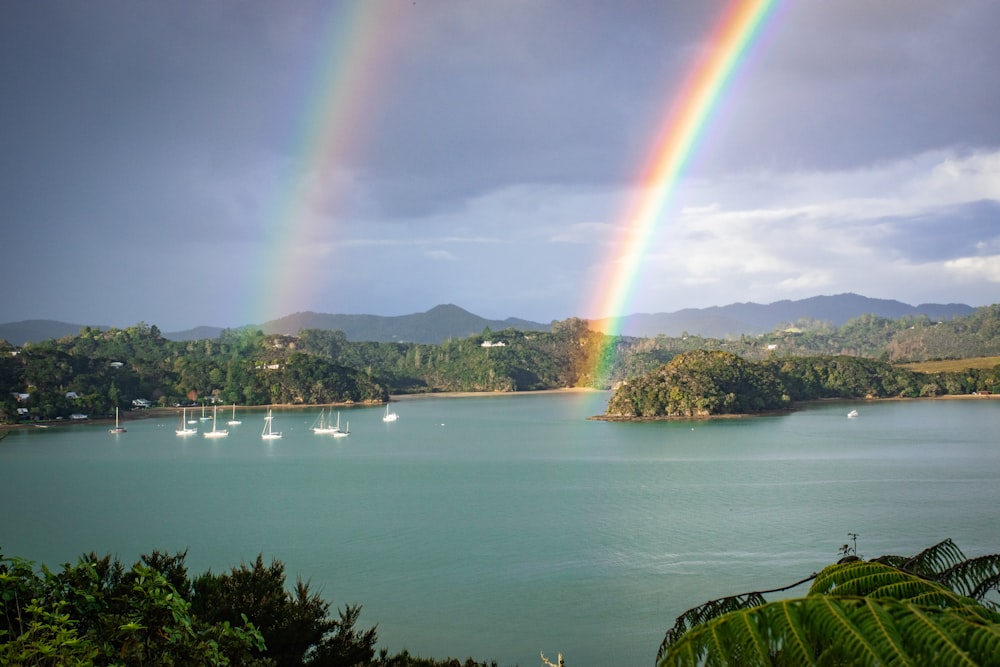 two rainbows over a lake with boats in the water