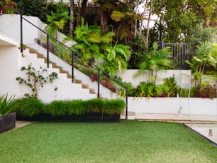 a white house with a green lawn and stairs