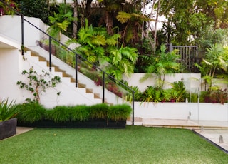 a white house with a green lawn and stairs