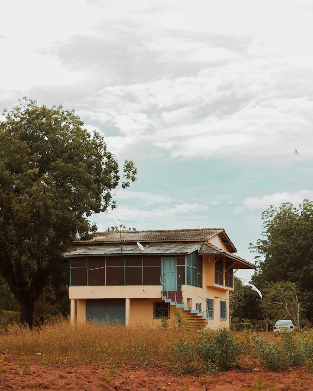 brown and white wooden house surrounded by green trees under white clouds during daytime