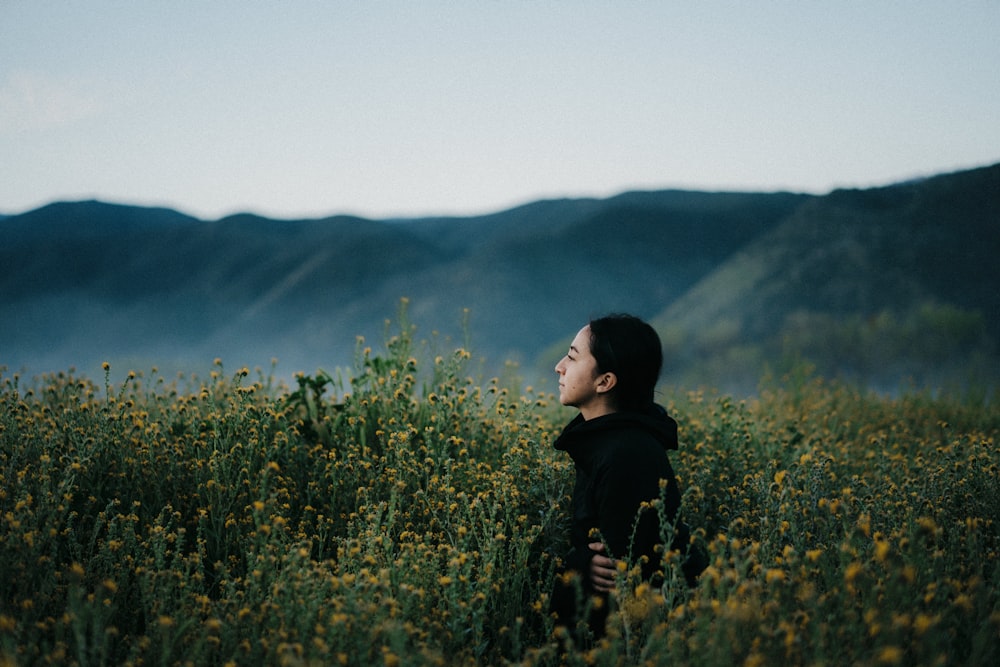 woman in black jacket standing on green grass field during daytime