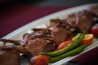 Close-up of suya-spiced lamb chops grilled to perfection, garnished with fresh herbs.