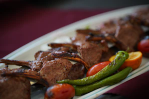 A rustic platter featuring lamb chops alongside coarse salt and pepper.