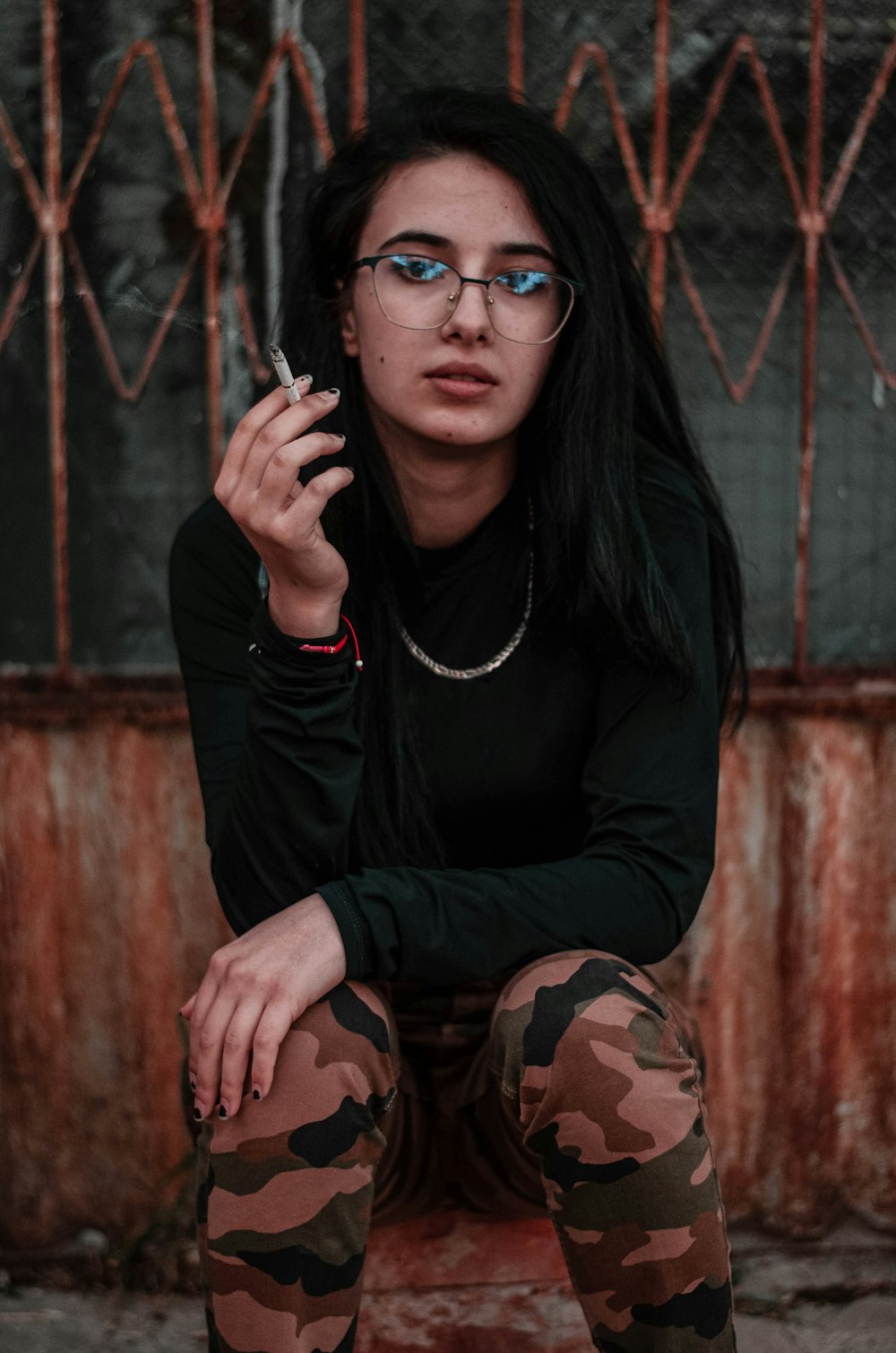 woman in black long sleeve shirt and brown camouflage pants wearing black framed eyeglasses